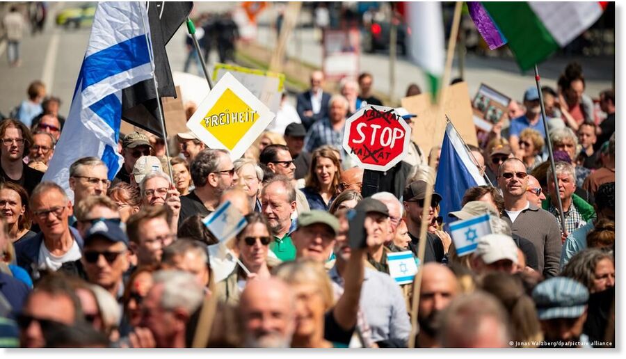 Click to enlarge Demonstrators hold up signs reading