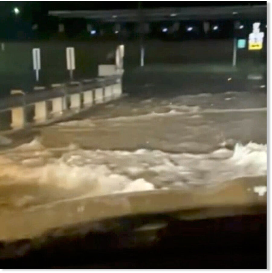 In a still from a video filmed through the windshield of a car, flood water surges across a bridge in Yellville, Ark.