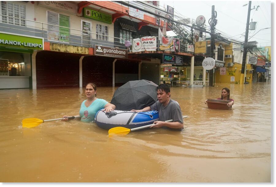 Click to enlarge Residents use rubber paddles from a toy boat as they wade along a flooded street caused by heavy rains from Tropical Storm Yagi, on Monday, Sept. 2, 2024