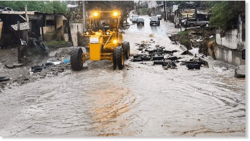 Crews work to clear damage in a flooded street.