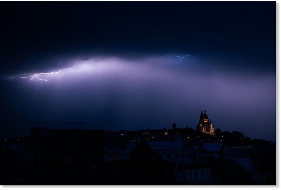 Click to enlarge A lighting bolt lights up the sky over Sacre Coeur Basilica in Montmartre during a thunderstorm, northern Paris, on June 25, 2025