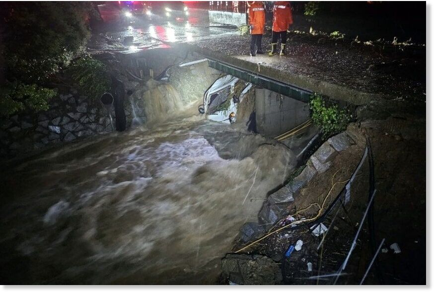 A 1-ton truck swept away by floodwaters is submerged in a stream