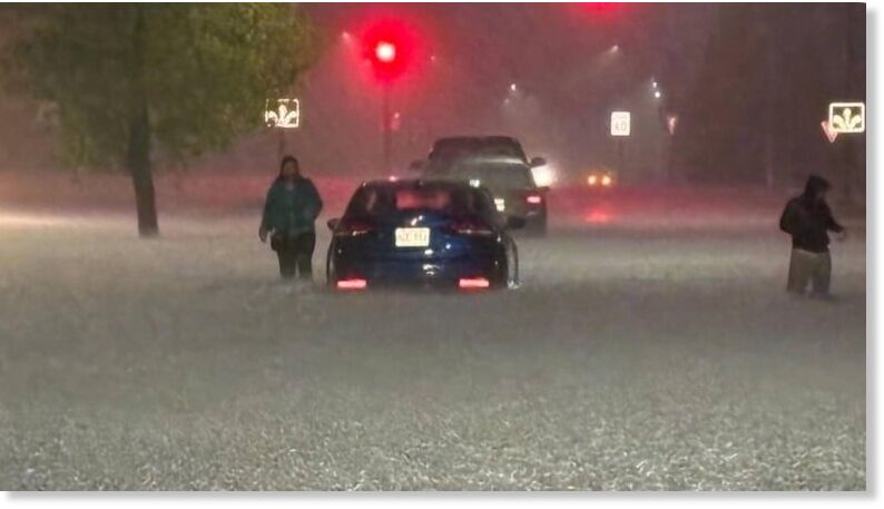 People walk near stranded cars at the flooded intersection of McKenzie Avenue and Brandt Street in Steinbach around 1 a.m. Friday.
