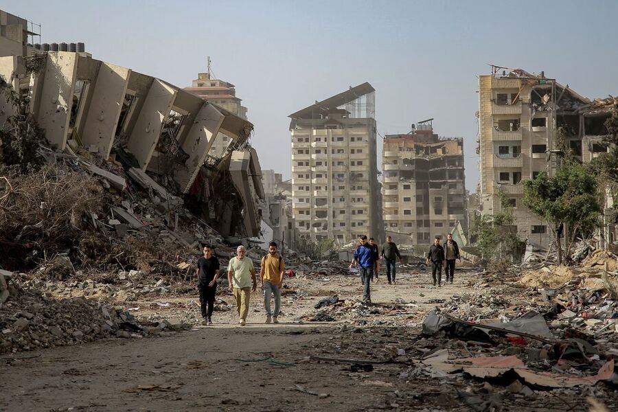 Click to enlarge Palestinians walk amid the rubble of destroyed buildings in Gaza City’s Tal al-Hawa district on 26 November 2023