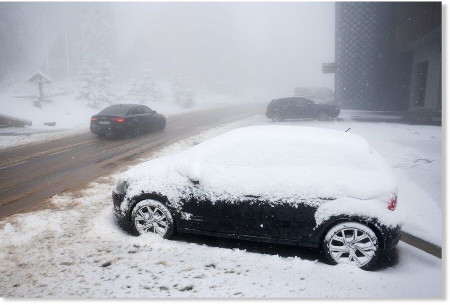 A car drives along a road during an unexpected snowfall on mountain Jahorina near Sarajevo, Bosnia, Thursday, Oct. 2, 2025.