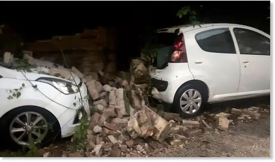 Click to enlarge A wall collapsed due to the storm in Cordu, crushing parked cars beneath the debris.