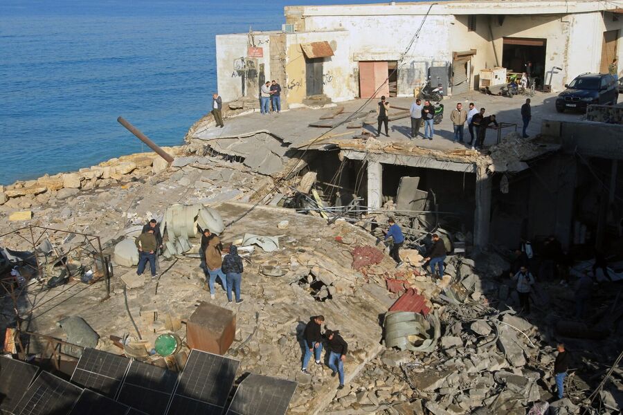 Click to enlarge People gather at the site of a building that was destroyed by an Israeli strike in the industrial area of Ghazieh town