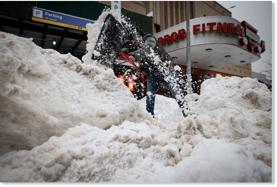 worker clears snow from the entrance to a parking lot, as a major winter storm spreads across a large swath of the United States, in New York City, on Jan. 26, 2026.