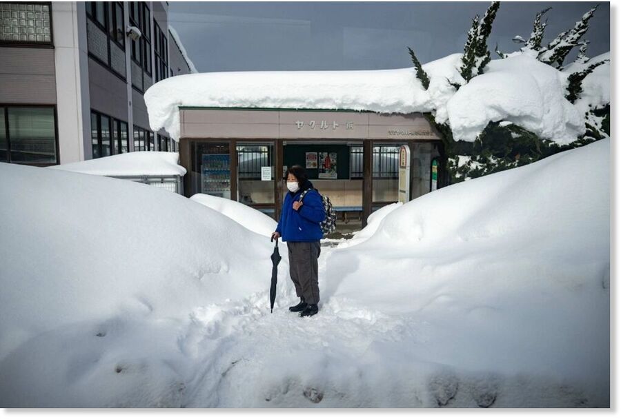 Click to enlarge A passenger waits in front of a snow-covered bus stop in the city of Aomori on Friday.
