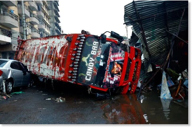 A public transport bus known as matatu lies on top of a private car as a result of heavy rainfall in the Grogan area, popular for automotive workshops and secondhand spare parts, in downtown Nairobi, Kenya, March 7, 2026.