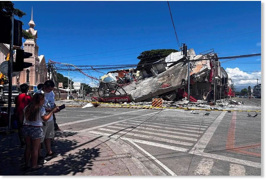 People stand near a collapsed building after a magnitude 7.8 quake in General Santos, Philippines, June 8, 2026.