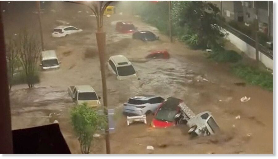 Click to enlarge Vehicles are swept away by flooding in Hebei Province.