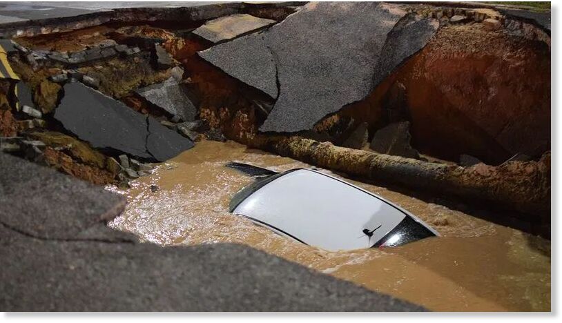 Click to enlarge Water rushes over a car that has plunged into a sinkhole in east Baltimore.