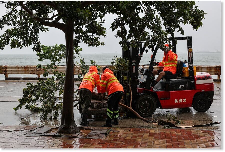 Click to enlarge Workers clear fallen debris and obstacles from the road after Typhoon Noul hit Hong Kong on Sunday.