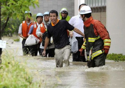 Click to enlarge Local residents wade through a flooded street