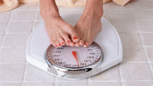 Click to enlarge A dieter checks weight on a bathroom scale.