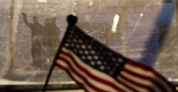 Click to enlarge Iraqis wave as the last U.S. convoy heads