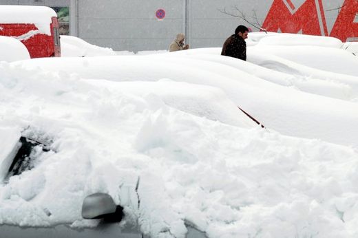 A man walks between cars covered with snow in Podgorica.