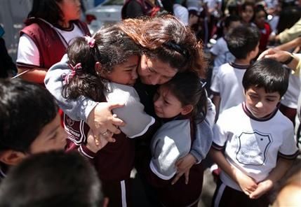 A woman comforts her children outside a school at the Roma neighborhood after a earthquake felt in Mexico City