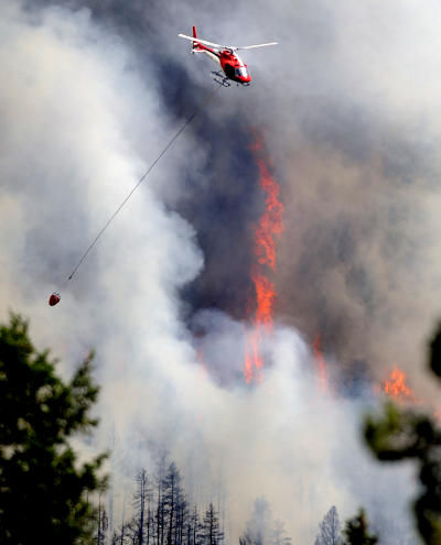 Click to enlarge A firefighting helicopter flies above the fire near Bison Drive on Tuesday west of Boulder.