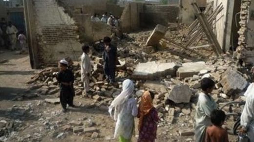 Children gather near a house destroyed