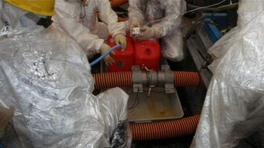 Fukushima: Workers in protective suits examine pipes