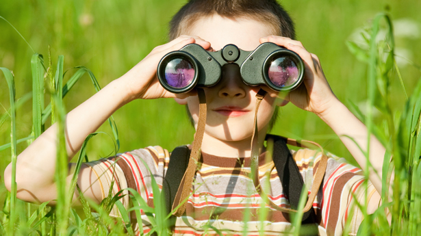 Young Boy In A Field Looking Through Binoculars,